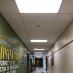 Bright LED ceiling panels installed in a hallway using LED Magnetic Retrofit Kit for 2x2 Parabolic Troffer 5-CCT