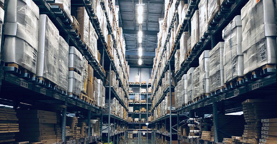 Eight-foot LED tube light fixtures in warehouse ceiling demonstrating proper aisle lighting placement to reduce shadows on storage racks