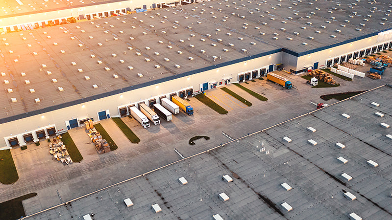 Overhead view of warehouse loading dock area with multiple bay doors and LED high bay lights illuminating shipping and receiving operations