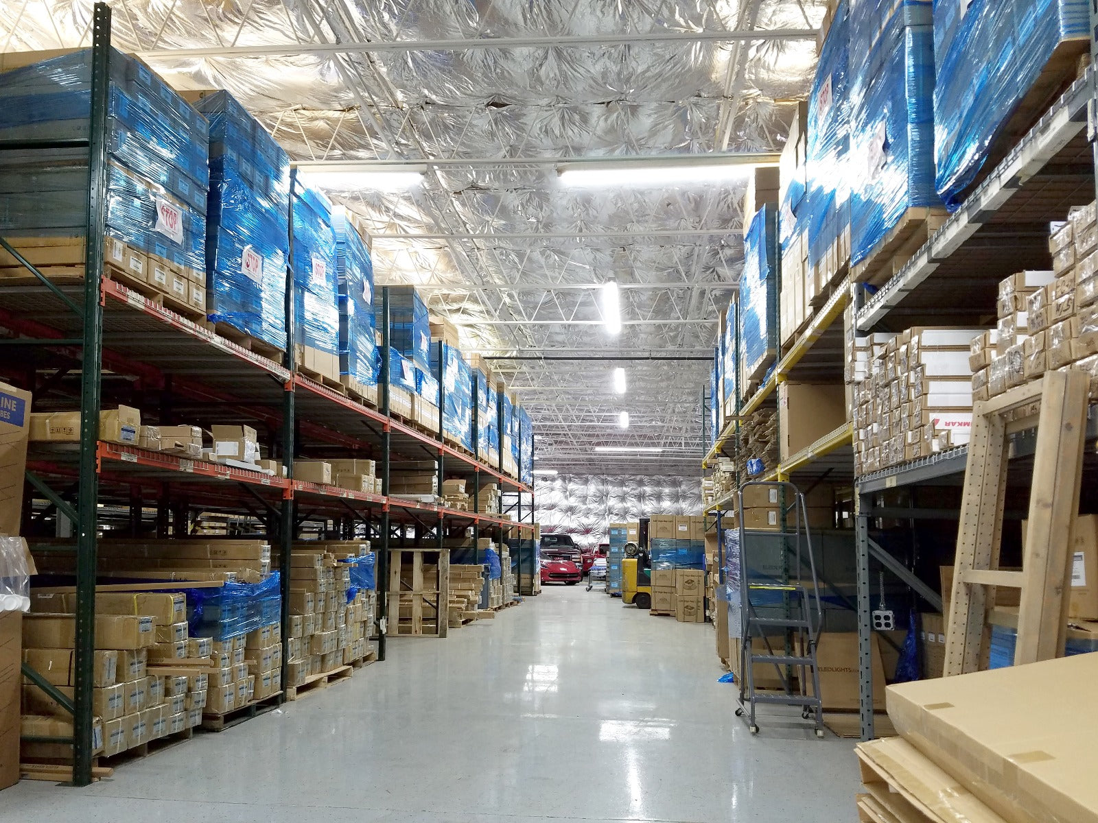 LED linear high bay lights illuminating warehouse aisle with tall storage racking showing proper vertical and horizontal illumination