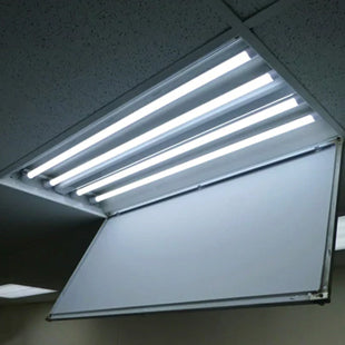 2x4 fluorescent troffer fixture in a suspended grid ceiling is open to reveal 4 LED tubes that have been installed to retrofit the fixture from fluorescent to LED